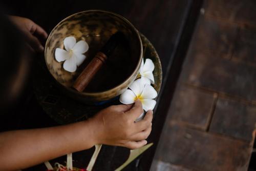 a person holding white flowers in a bowl at The Damai in Lovina