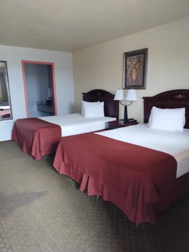 Cette chambre d'hôtel comprend 2 lits avec des draps rouges. dans l'établissement Howards Inn Motel, à Eunice