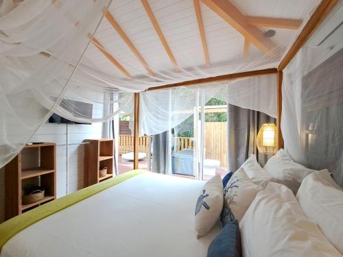 a bedroom with a bed with white sheets and pillows at Residence De La Cousiniere in Vieux-Habitants