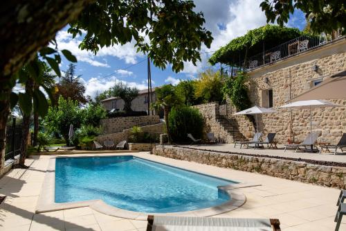 una piscina en un patio con sillas y un edificio en Domaine de la Pinède en Aubenas