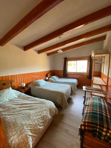 a bedroom with three beds and a window at Cabaña Malalcahuello con playa de Rio in Malalcahuello