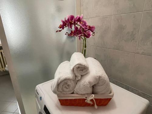 Una cesta de toallas y un jarrón de flores. en Ca' Mariuccia appartamento in Venaria Reale, en Venaria Reale