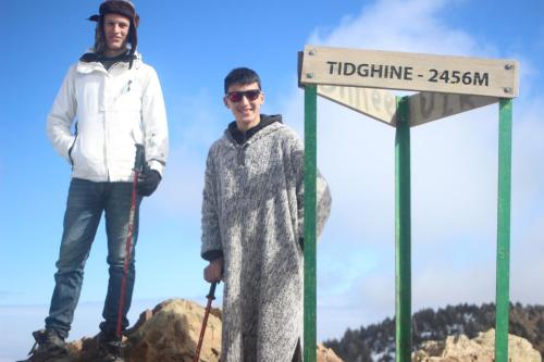 two people standing next to a sign at the top of a mountain at azila _ issagun 