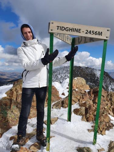 a man standing next to a sign at the top of a mountain at azila _ issagun 