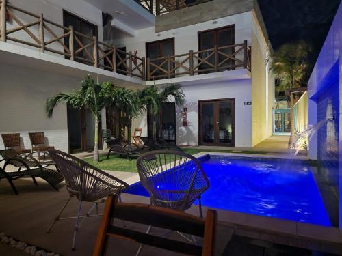 una piscina con 2 sillas y una casa en Pousada Solarium en Canoa Quebrada