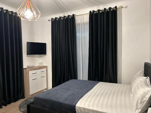 a bedroom with black curtains and a bed and a tv at Pensiunea Le Patrick in Afumaţi