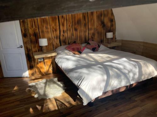 1 dormitorio con 1 cama con pared de madera en Bungalow Hoodoo, en Melipeuco