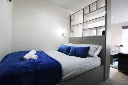 een slaapkamer met een groot bed met blauwe kussens bij Lovely Studio Flat in Bolton in Bolton