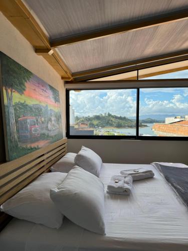 グアタペにあるHotel Stay Guatape a dos cuadras del parqueのベッドが2つと大きな窓がある寝室