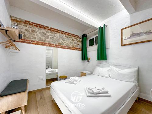 Schlafzimmer mit einem weißen Bett und grünen Vorhängen in der Unterkunft MareMò Accomodations - Rooms in Tropea in Tropea