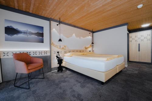 a bedroom with a large bed and a chair at Hotel Central Wolter - Grindelwald in Grindelwald