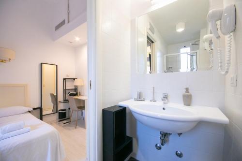 a white bathroom with a sink and a bed at Caffe' e Cuscino in Rome