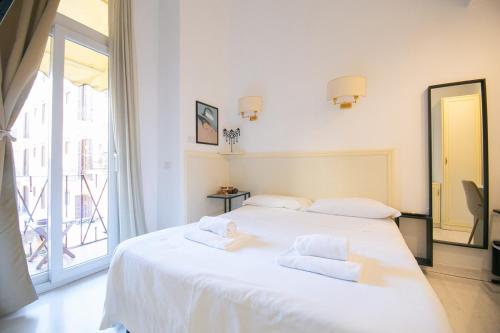 a white bed in a room with a large window at Caffe' e Cuscino in Rome