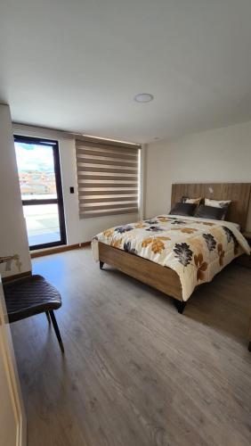 um quarto com uma cama, uma cadeira e uma janela em La Terraza departamentos 401 em Cuenca