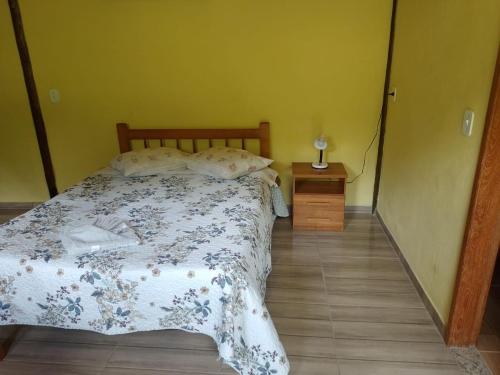 a bedroom with a bed with a floral bedspread at Chalés pouso do vale in Visconde De Maua