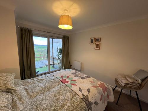 a bedroom with a bed and a window at Otter Holt, beautiful East Devon in Tipton Saint John
