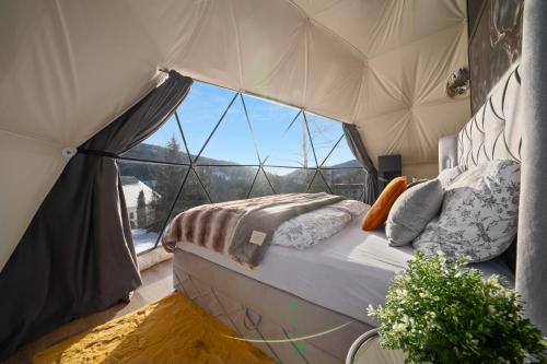 a bedroom with a bed in a tent with a large window at Glamping Špindl in Špindlerův Mlýn