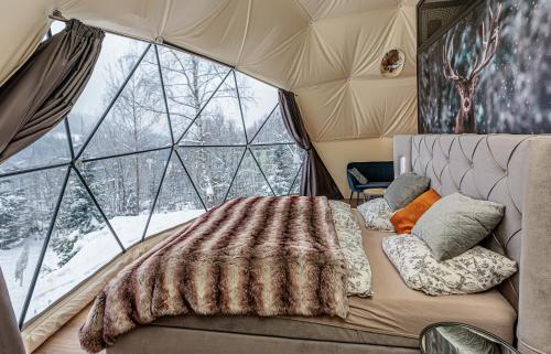 a bed in a room with a large window at Glamping Špindl One&Only in Špindlerův Mlýn