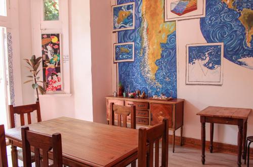 un comedor con una mesa y una pintura en la pared en Nómada Eco-Hostal, en Valparaíso
