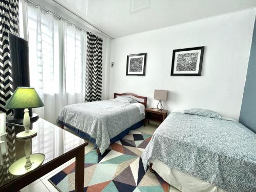 Pedro Vicente MaldonadoにあるDepartamento 2 habitaciones- Piscina, Botánico, BBQ, Terraza - THE GARDEN HOUSEのベッドルーム1室(ベッド2台、ガラス張りのテーブル付)