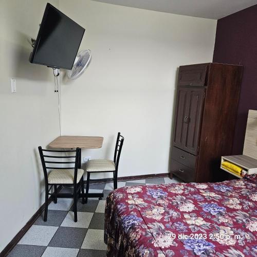 una camera da letto con un letto, un tavolo e una TV di Hostal La Cascada a Lima