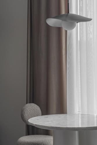 une table blanche, deux chaises et un rideau dans l'établissement Sleek and New Studio, Monaco, à Beausoleil