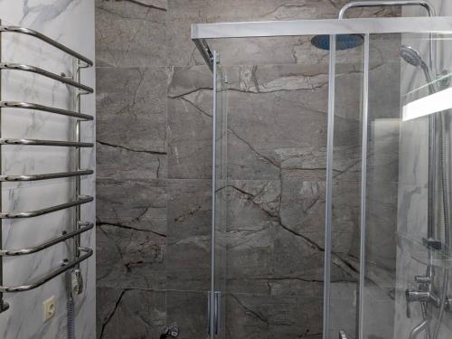 a shower in a bathroom with a stone wall at ALIANCE апартамети в центрі міста. in Ivano-Frankivsk