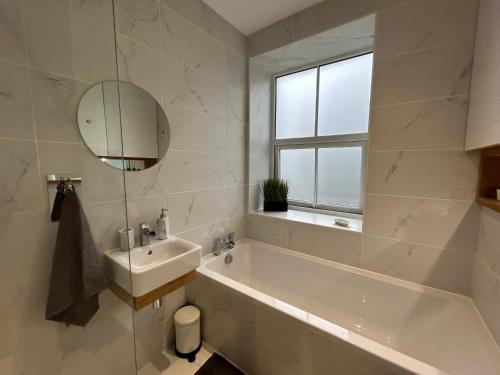 a bathroom with a tub and a sink and a mirror at Cottage in Holmfirth Centre in Holmfirth