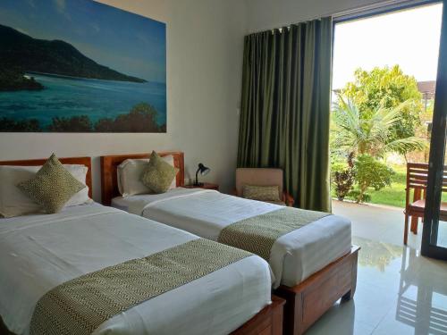 two beds in a room with a large window at The Happinezz Hills Hotel in Karimunjawa