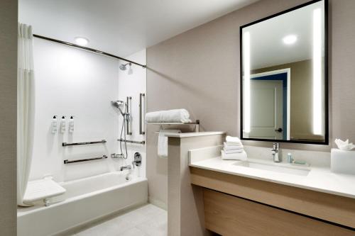 a bathroom with a tub and a sink and a mirror at TownePlace Suites by Marriott Show Low in Show Low