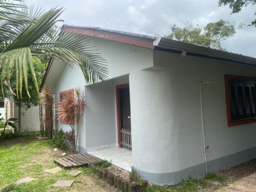 ein weißes Haus mit einer Palme davor in der Unterkunft Casa de veraneio in Arroio do Sal
