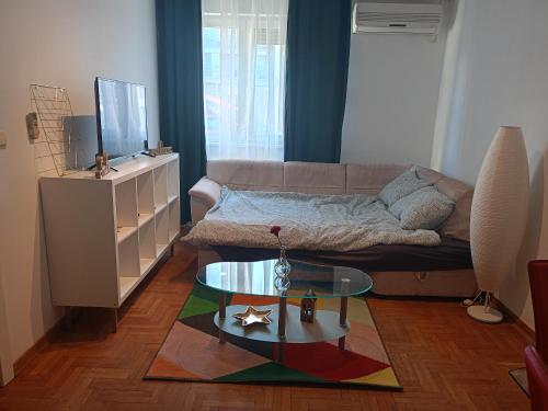 uma sala de estar com um sofá e uma mesa de vidro em Clockwork orange apartment em Vračar (historical)