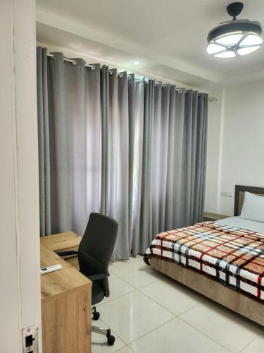 a bedroom with a bed and a desk and a chair at Robert's Place Block A 202 in Baatsona