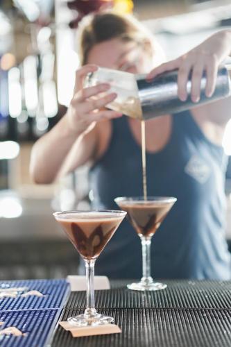 a woman pouring a drink into two martini glasses at The Suites at Fishermen's Village - 2 Bedroom Suites in Punta Gorda