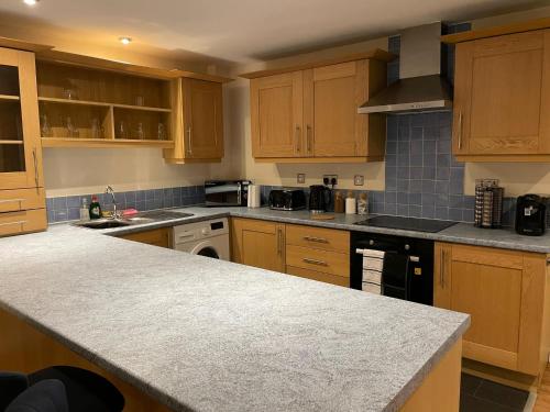 a kitchen with wooden cabinets and a counter top at Modern 2 BDR Flat in Nottingham City Centre with FREE Parking in Nottingham