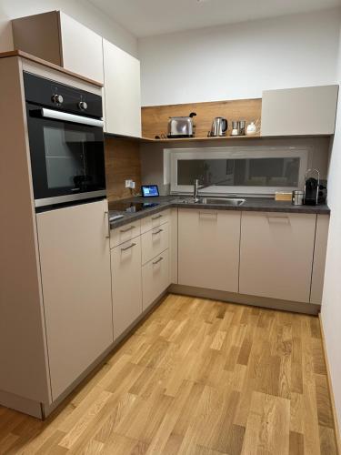 a kitchen with white appliances and a wooden floor at Harmony Living - 10 min to Graz in Lassnitzhöhe