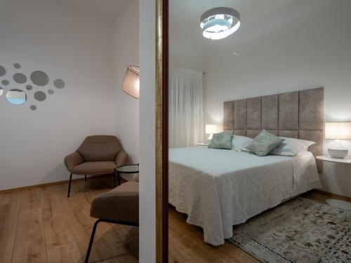 ein Schlafzimmer mit einem Bett, einem Stuhl und einem Spiegel in der Unterkunft Adam 2 in Stobreč