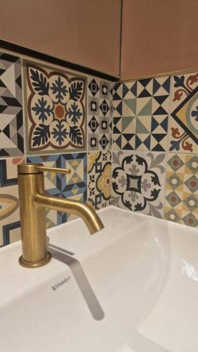 a bathroom sink with a gold faucet and tiles at High street, Bruton in Bruton