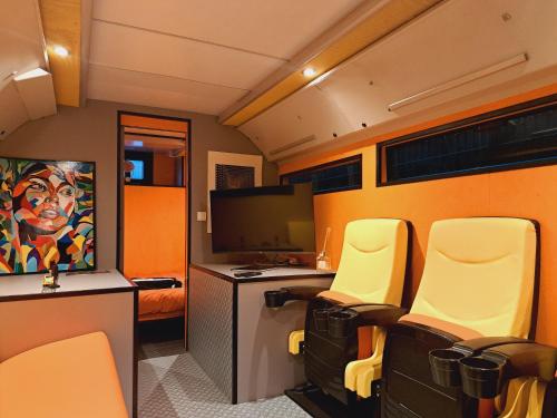 Cette chambre dispose de chaises, d'un bureau et d'une télévision. dans l'établissement Le Bus - Changer d'air en Moselle, à Longeville-lès-Saint-Avold