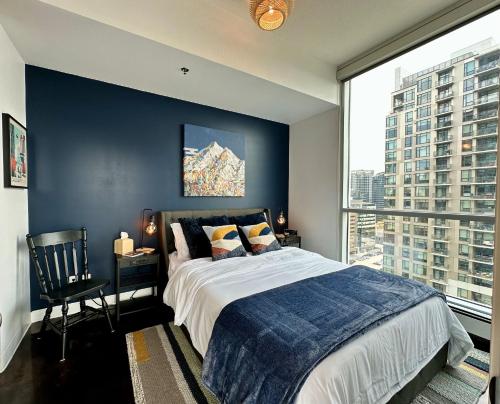 a bedroom with a large bed with a blue wall at ColoursNest - Downtown apt spectacular view and location in Calgary