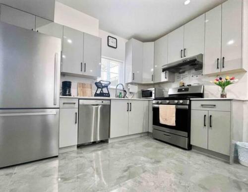 a kitchen with white cabinets and stainless steel appliances at Vancouver’s Homey Laneway House in Vancouver