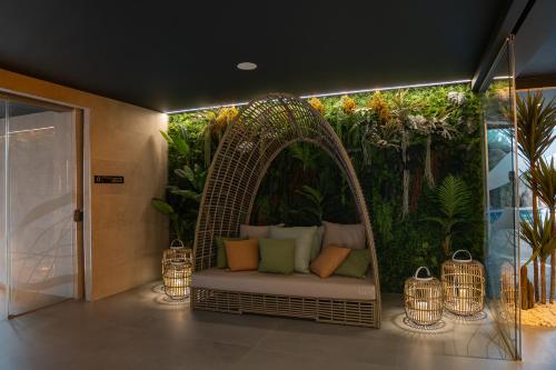 uma sala com um banco de vime em frente a um jardim em Alambique - Hotel Resort & Spa no Fundo