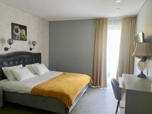 a bedroom with a large bed and a window at Apartamentai Ornamentai in Druskininkai