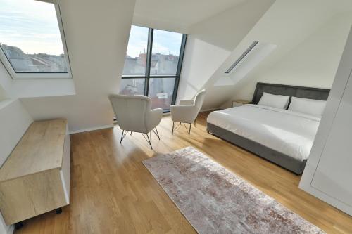 a bedroom with a bed and two chairs and windows at Vienna Lotus Apartments in Vienna