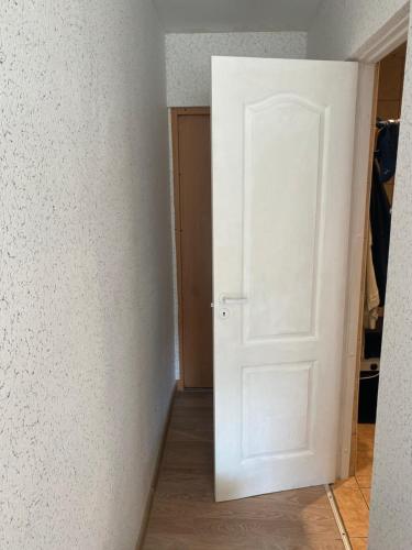 an empty room with a white door and wooden floors at Mini room in Kėdainiai