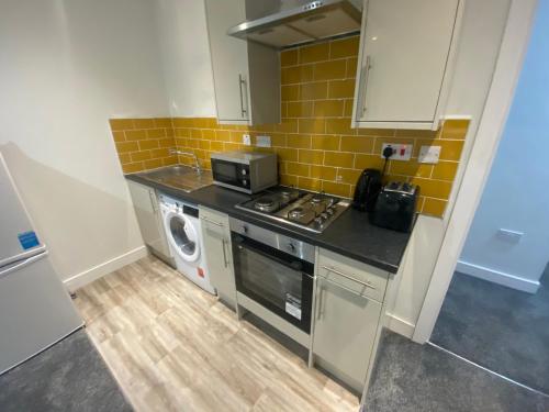 een kleine keuken met een fornuis en een magnetron bij Cosy town centre flat in Bolton