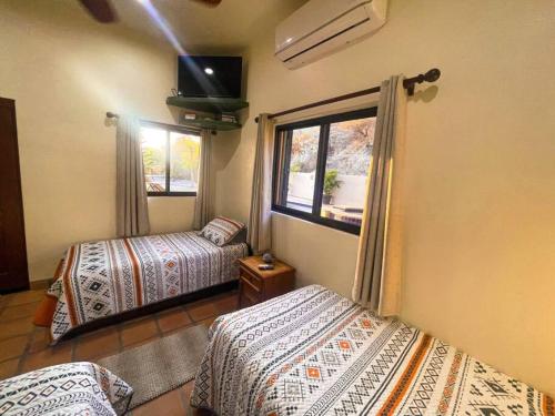two beds in a room with a window and a tv at Private Home with Pool and Spa - Kayaks, Quad Rental in Las Palmas