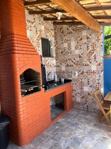 an outdoor brick fireplace with a television on top at Casa com piscina para temporada - Unamar, Cabo Frio - RJ in Cabo Frio