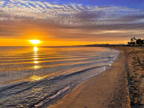 a sunset on a beach with the sun setting at Private Home with Pool and Spa - Kayaks, Quad Rental in Las Palmas