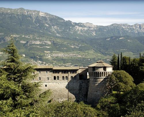a building on a hill with mountains in the background at Hotel Sant'Ilario in Rovereto